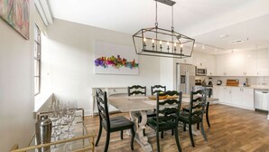 Una cucina moderna con pensili bianchi, un tavolo da pranzo in legno e una lampada a sospensione.