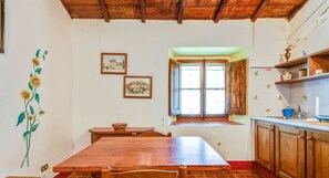 Un'area pranzo con un tavolo e sedie in legno, una finestra con tende e un muro decorato con un murale di girasoli.