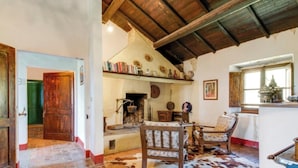 A rustic room with a wooden ceiling, a fireplace, a cowhide rug, and a chair with floral upholstery. - Exclusive Apartment With Fireplace (Castelfranco Piandisco)
