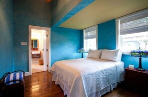 Une chambre à coucher avec un lit, une table de chevet, une lampe et une fenêtre.