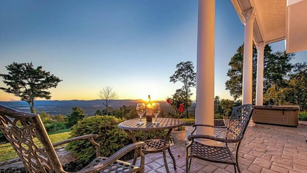 An outdoor patio with a table set for two, a chair, and a planter. - Private 12-Acre Mountain Estate with Blue Ridge Views, Game Room & Sleeps 20 (Fletcher)