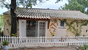 A rustic house with a tiled roof, a white picket fence, and a gravel driveway. - Charmante Maisonnette au Calme (Montmeyan)