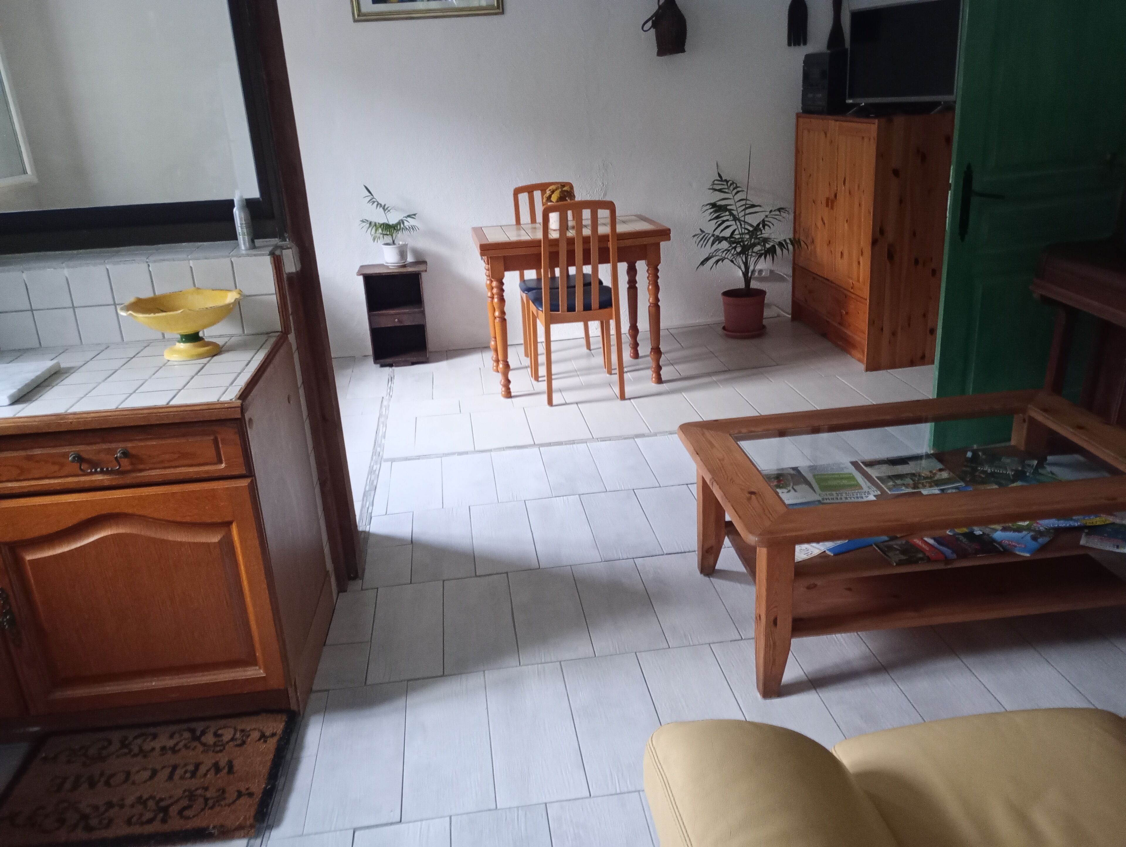 A kitchen with a wooden table, chairs, and a dining area. There is a wooden cabinet and a potted plant.