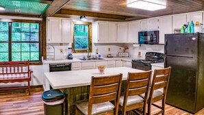A kitchen with white cabinets, a black refrigerator, wooden chairs, and a dining table.