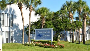 Un panneau indiquant « Fernadina Shores », situé au 631, avenue Tarpon, avec un bâtiment blanc et des palmiers en arrière-plan.