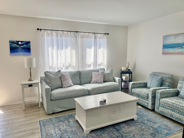 A living room with a grey sofa, a white coffee table, and patterned armchairs. - Walk to Beach - Updated Amelia Island Townhome Near Fort Clinch and Downtown (Fernandina Beach)