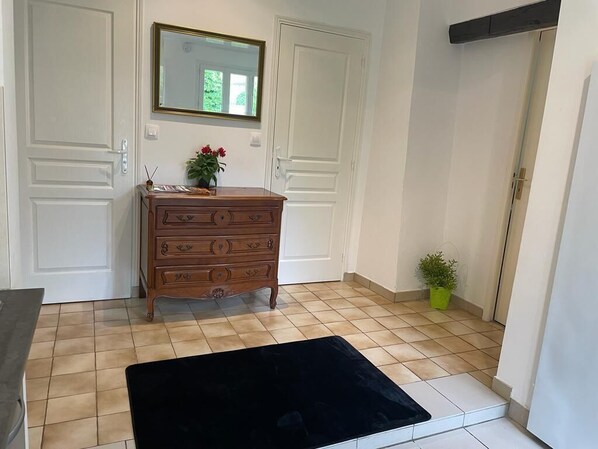 A room with a wooden dresser, a black rug, a mirror, and a small potted plant.