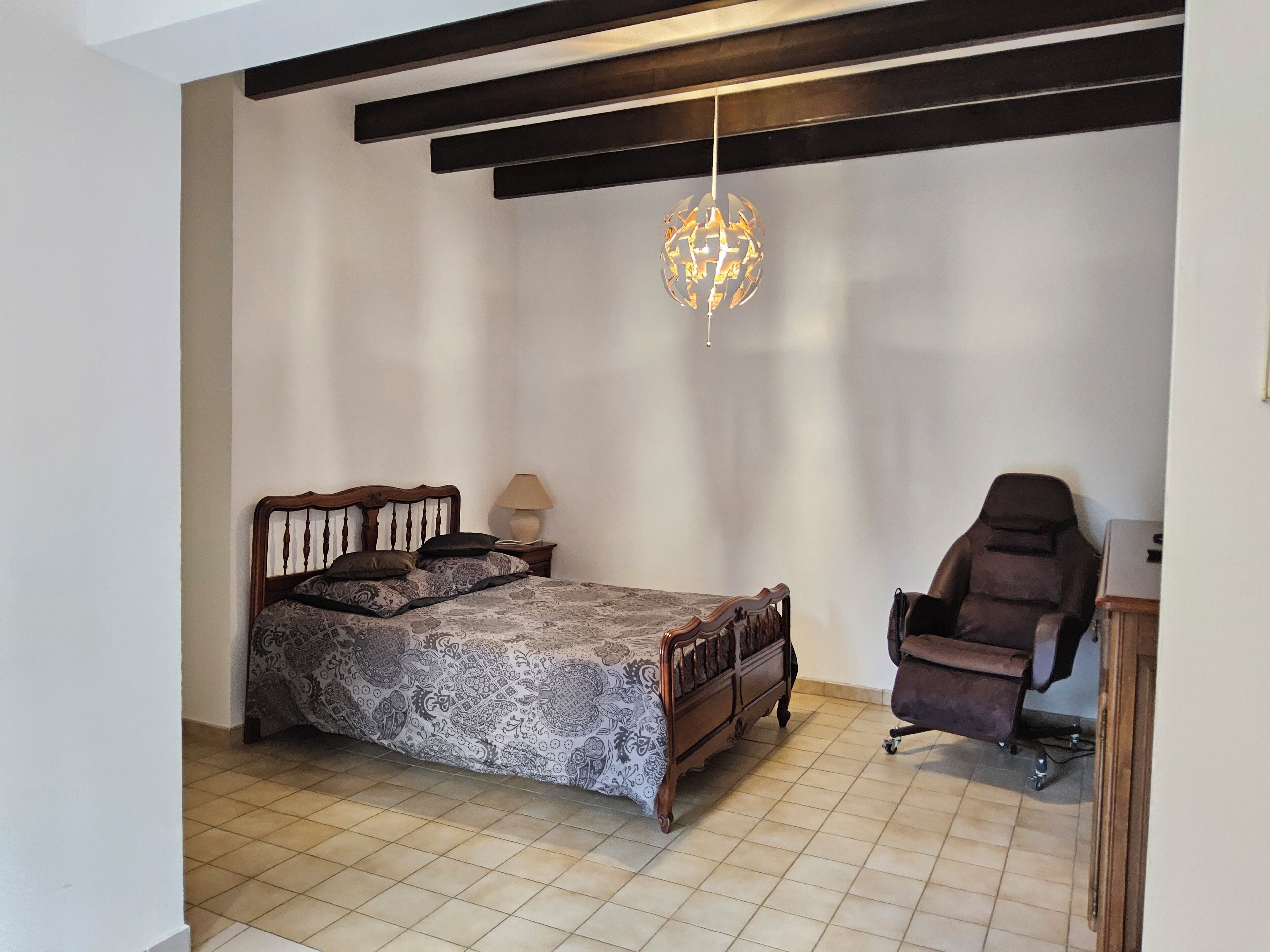 Ein Schlafzimmer mit einem Bett, einem Sessel, einer Lampe und einer Pendelleuchte.