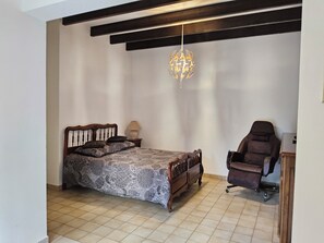 Een slaapkamer met een bed, een stoel, een lamp en een hanglamp.