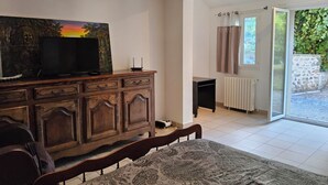 Un dormitorio con cama, cómoda, televisor y ventana con cortinas.
