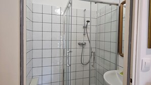 A modern bathroom with a glass-enclosed shower, a white sink, and a tiled floor. - Chambre Giverny (Hargeville)