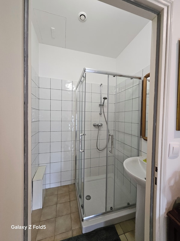 A modern bathroom with a glass-enclosed shower, a white sink, and a tiled floor. - Chambre Giverny (Hargeville)