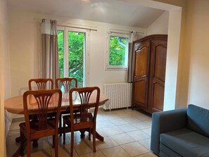 Een eetgedeelte met een houten tafel, stoelen, een radiator en een kast.