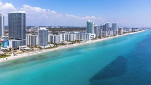 Eine Küstenstadt mit Wolkenkratzern, einem Strand und klarem türkisfarbenem Wasser.