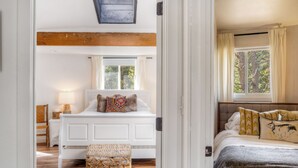 Une chambre à coucher avec un lit blanc, une fenêtre, une lampe et un panier en osier.
