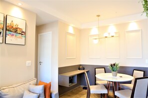 Uma sala de estar moderna com um sofá, uma mesa de centro e um espaço de jantar com cadeiras e uma mesa.