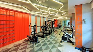 Ett gym med olika typer av träningsredskap, ett mönstrat golv och en röd vägg där ordet ”RESISTANCE” är skrivet.