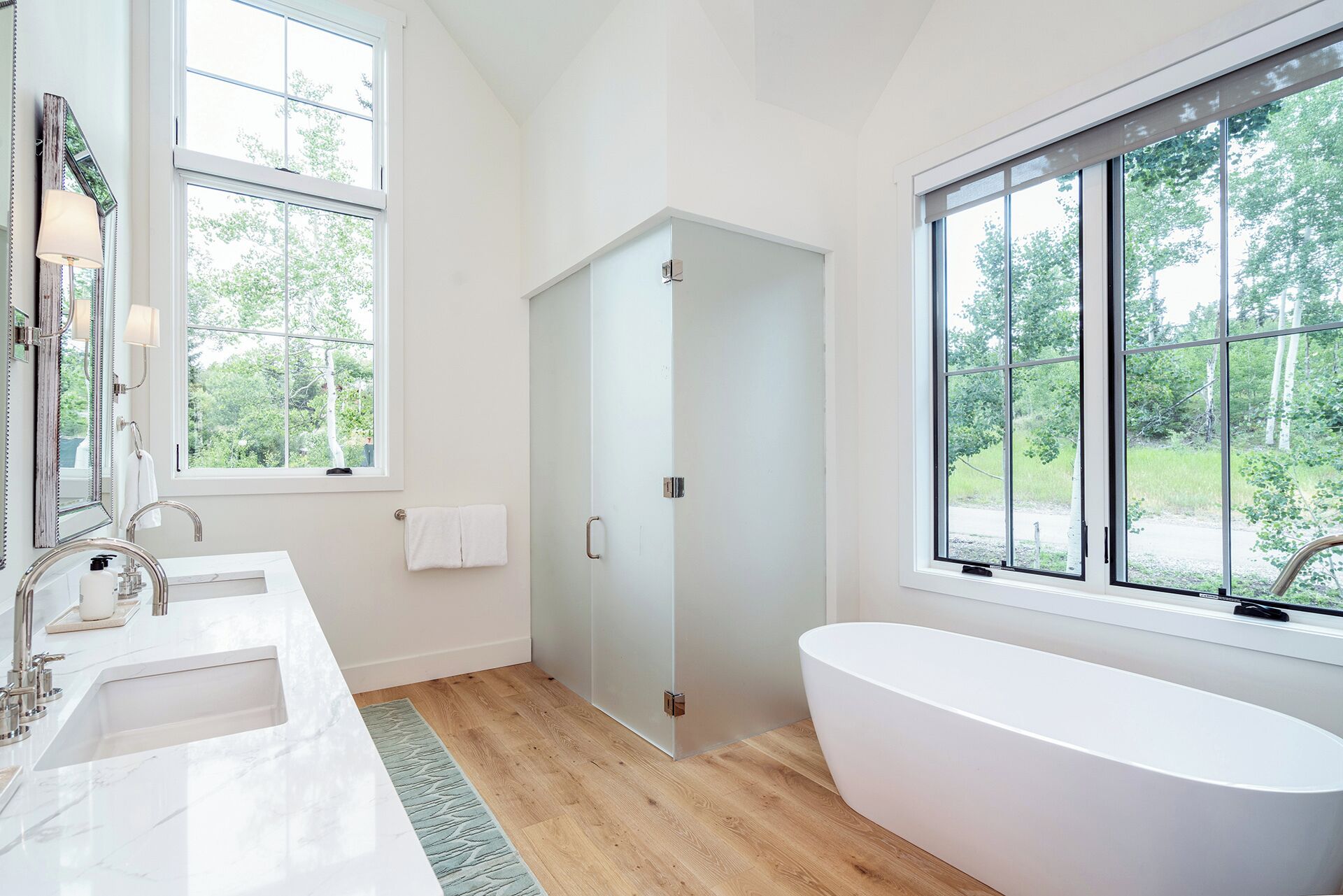 Un baño moderno con un ventanal grande, una bañera independiente y un lavabo doble.