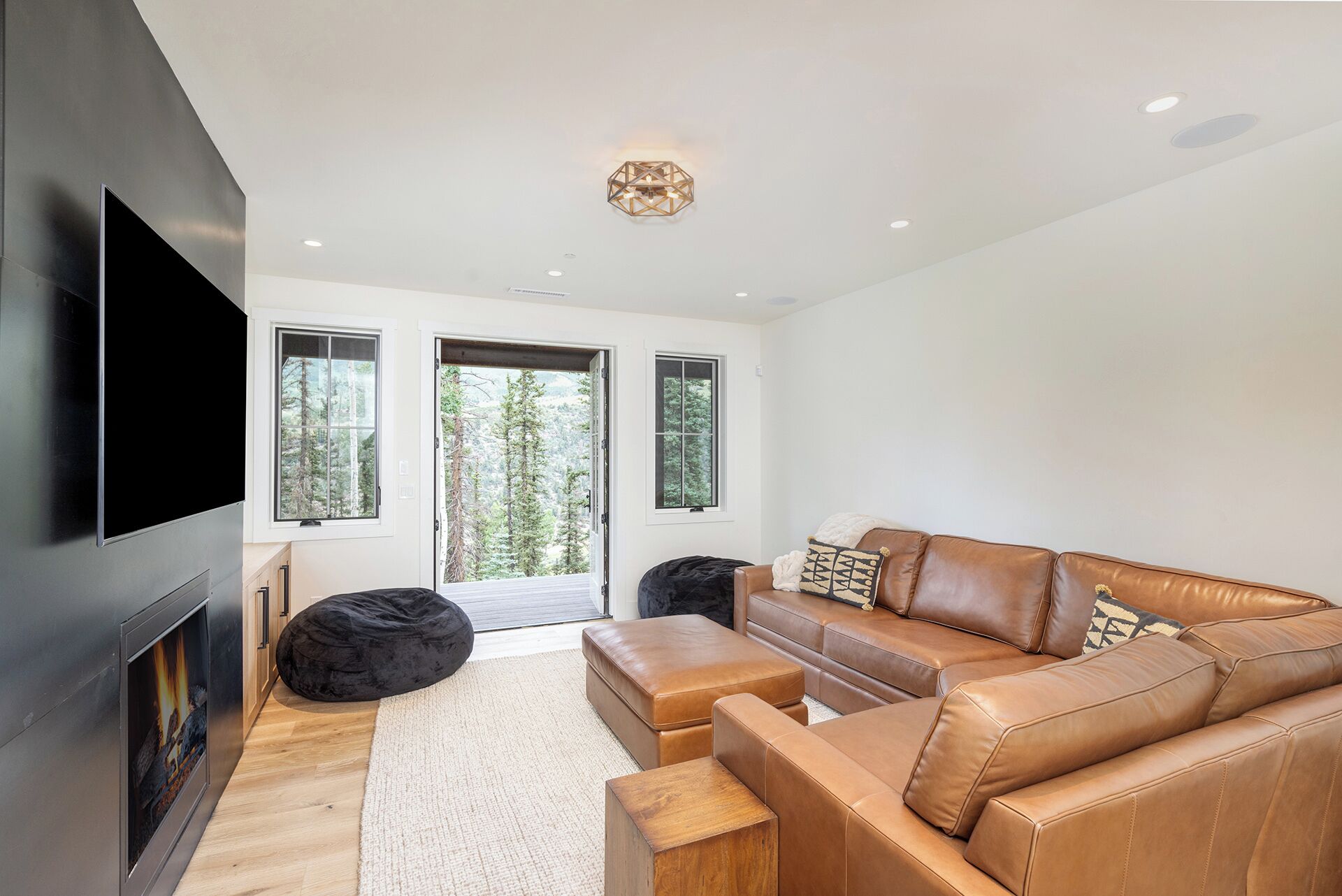 A modern living room with a leather sofa, a flat-screen TV, and a fireplace.