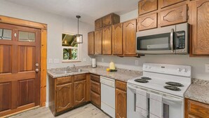 Una cocina con armarios de madera, microondas, estufa y lavavajillas.