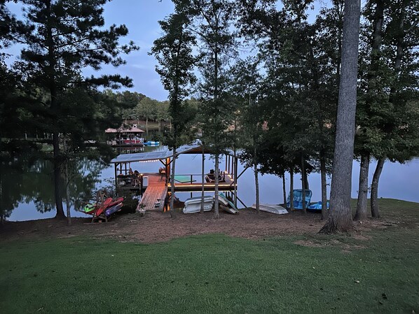 A lakeside cabin with a dock, surrounded by trees and a grassy area.