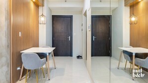 A modern hotel room with two wooden doors, a white tiled floor, and a small table with a chair. - Condo Unit in Uptown Parksuites T2 Bgc (Taguig)