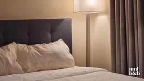 A hotel room with a tufted headboard, a bedside lamp, and a curtain. - Condo Unit in Uptown Parksuites T2 Bgc (Taguig)
