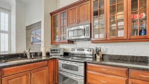 Una cocina con armarios de madera, microondas, estufa y un lavamanos.