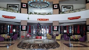 A spacious lobby with a central seating area, a Christmas tree, and a large chandelier.