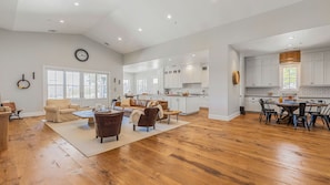 A spacious living area with a large wooden floor, a sofa, a coffee table, and a dining table with chairs.