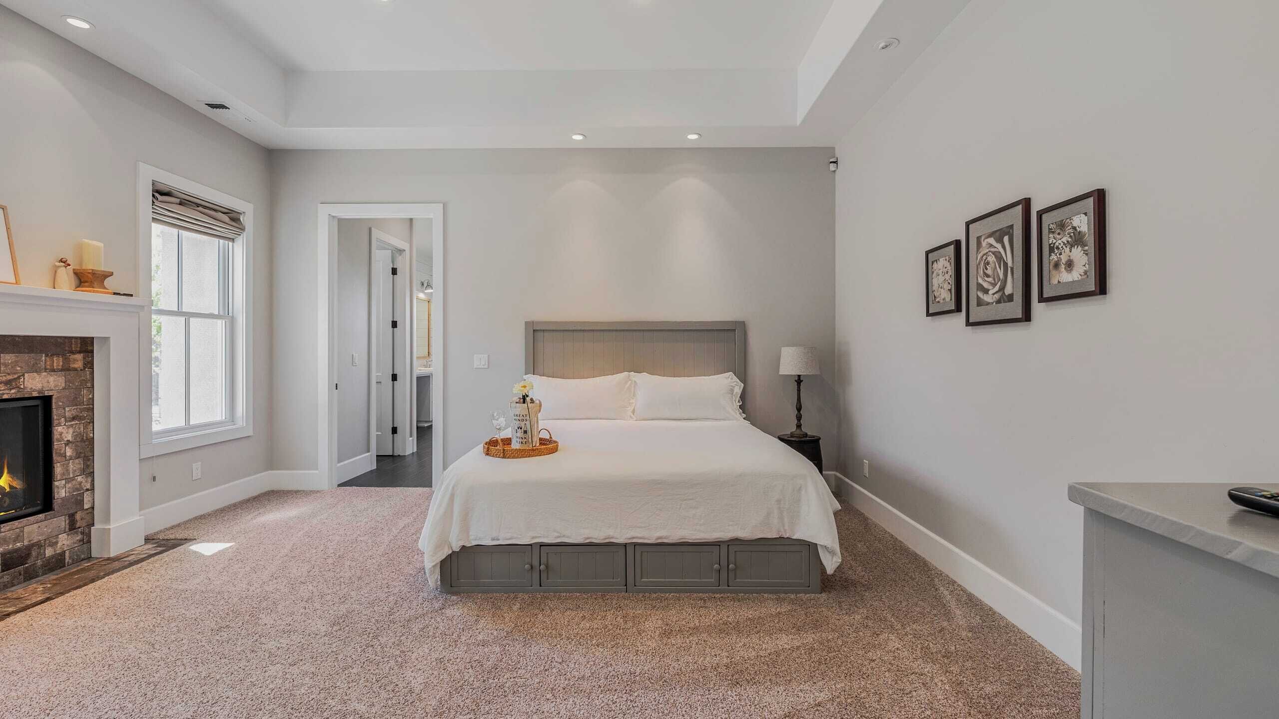 Een slaapkamer met een groot bed, een open haard en lijstwerken aan de wand.