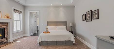 Een slaapkamer met een groot bed, een open haard en lijstwerken aan de wand.