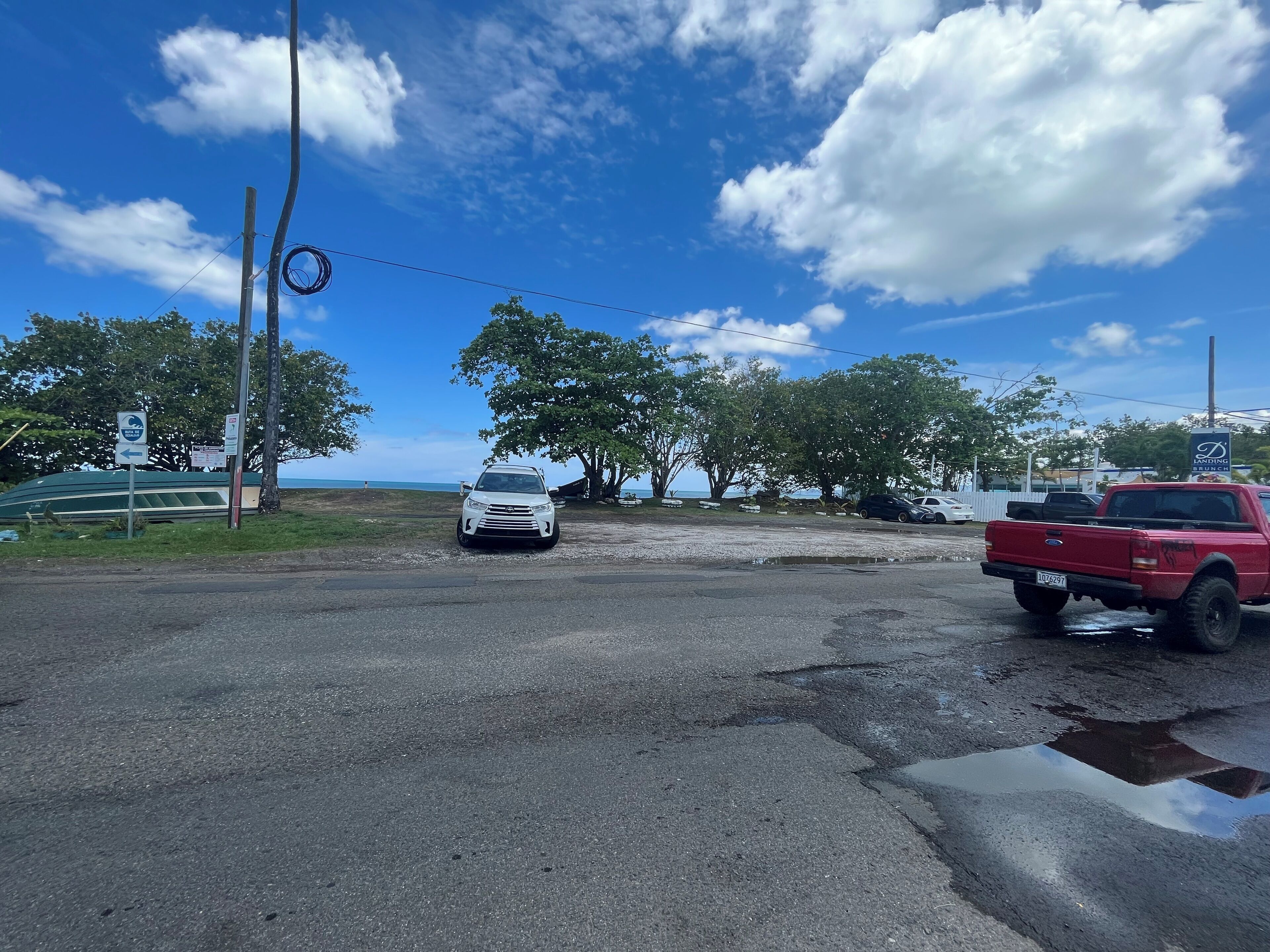 A parking area with a white car and a red pickup truck.
