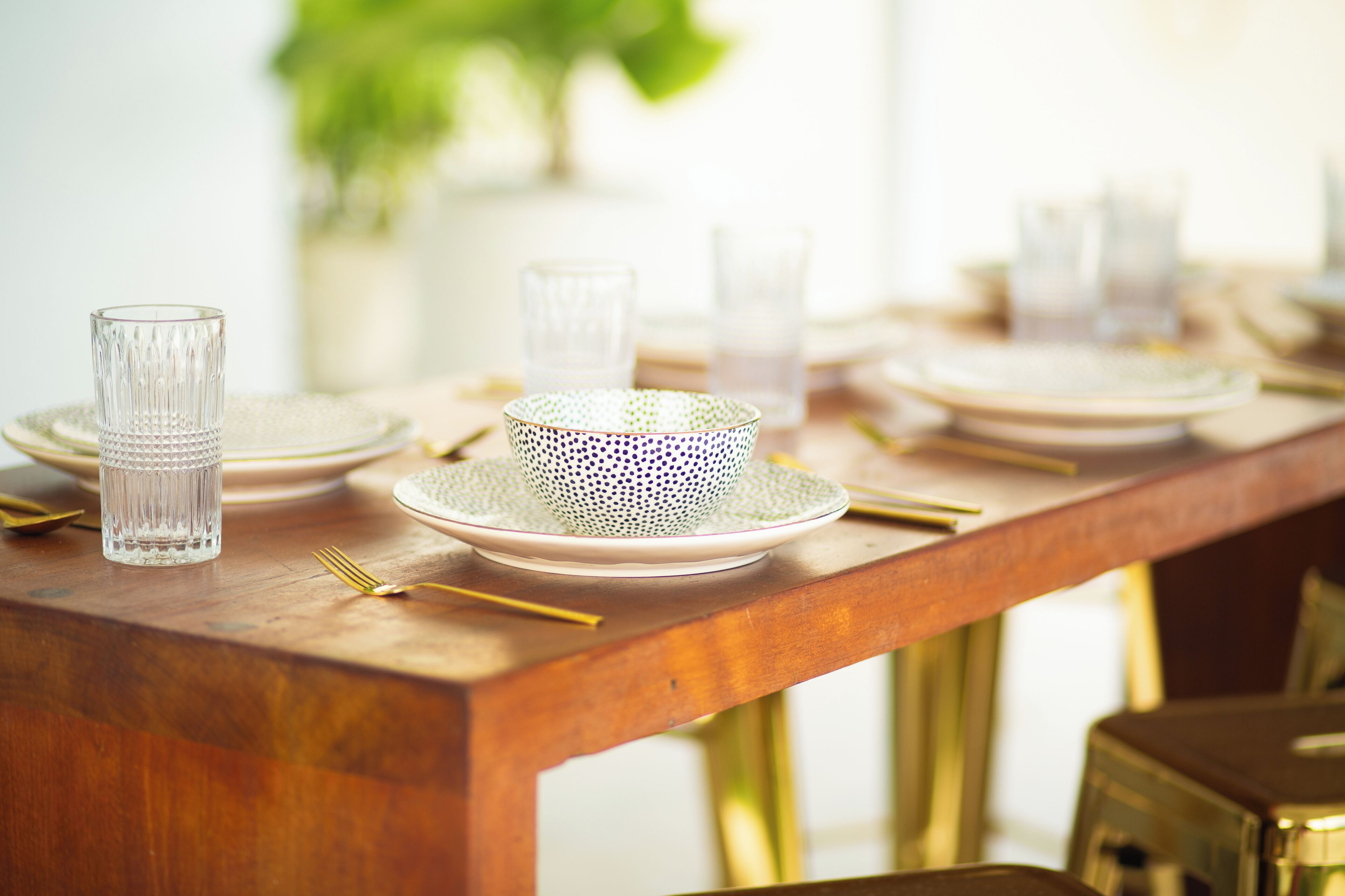 A wooden dining table set with plates, glasses, and cutlery.