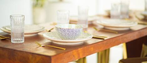 A wooden dining table set with plates, glasses, and cutlery.