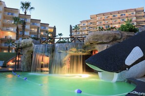 A hotel with a pool area featuring a waterfall and a rope swing.