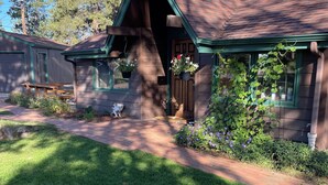Eine rustikale Holzhütte mit einem steilen Dach, einer Veranda mit einer Bank und hängenden Blumenkörben.