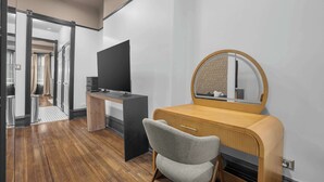 Une chambre à coucher moderne avec une coiffeuse en bois, un téléviseur et un miroir.