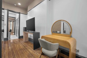 Une chambre à coucher moderne avec une coiffeuse en bois, un téléviseur et un miroir.