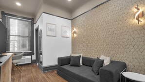 Un salon moderne avec un canapé, un bureau et une chaise. Deux tableaux encadrés sont accrochés au mur.