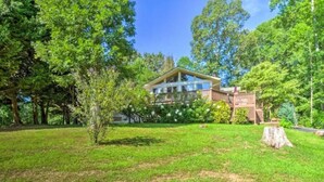 A house surrounded by a lush green lawn and trees. - Tranquility at Claire de Lune Mountain Lake Home (Hayesville)