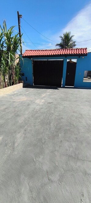 Um edifício azul com telhado de telhas vermelhas, duas portas de garagem abertas e piso de concreto.