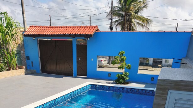 Ein rechteckiger Swimmingpool mit blauen Fliesen, umgeben von einer Betonplattform und Holzboden.