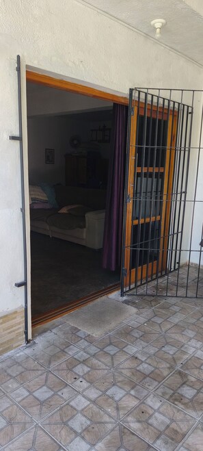 Uma porta aberta que dá para um quarto com uma cama, uma cômoda e um ventilador na parede.