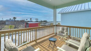 A balcony with wooden railings, a small round table, and two cushioned chairs. - Paradise on Copano Bay ~ Complementary Kayaks ~ Pier and Pool  (Rockport)