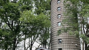 A cylindrical building with a small attached structure featuring a door and windows. - Owls Nest Silo - 100 y/o converted concrete silo (Elmdale)