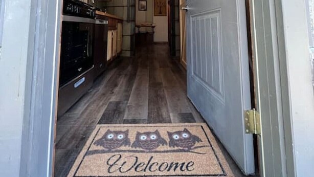 A wooden interior hallway leading to a kitchen with a welcome mat. - Owls Nest Silo - 100 y/o converted concrete silo (Elmdale)