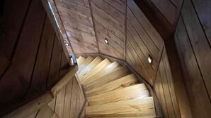 A wooden spiral staircase with a wooden finish, ascending to a higher level. - Owls Nest Silo - 100 y/o converted concrete silo (Elmdale)