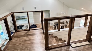A spacious loft with a high ceiling, wooden flooring, and a view of a dining area.