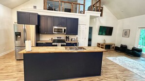 A modern kitchen with dark cabinets, stainless steel appliances, and a wooden island.